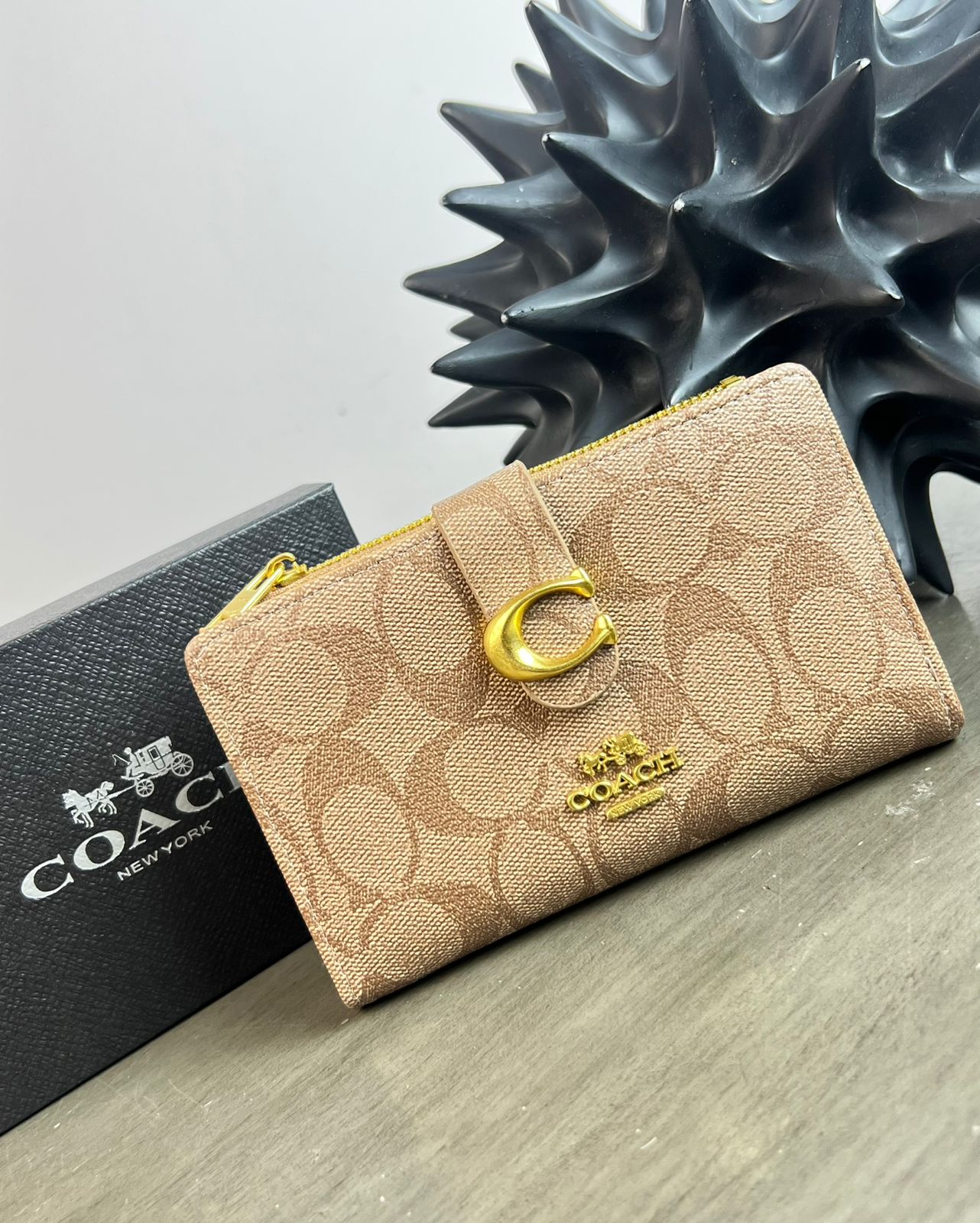 CARTERA COACH BROCHE CAFE CLARO CON ESTAMPADO